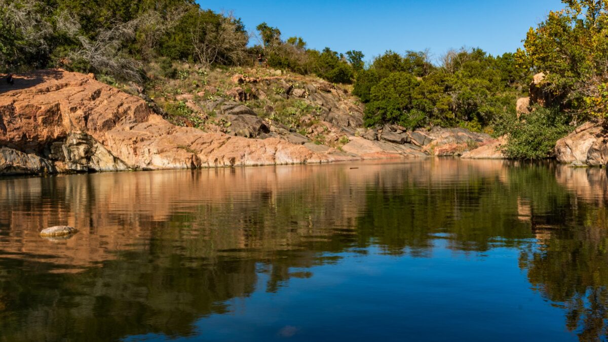 inks lake state park rock pink granite rock cliff with trees reflecting into lake