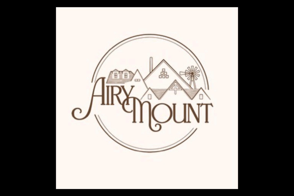 Logo for Airy Mount featuring stylized text integrated with line art of houses, a windmill, and a circular border, all in a brown monochrome palette on a light background.