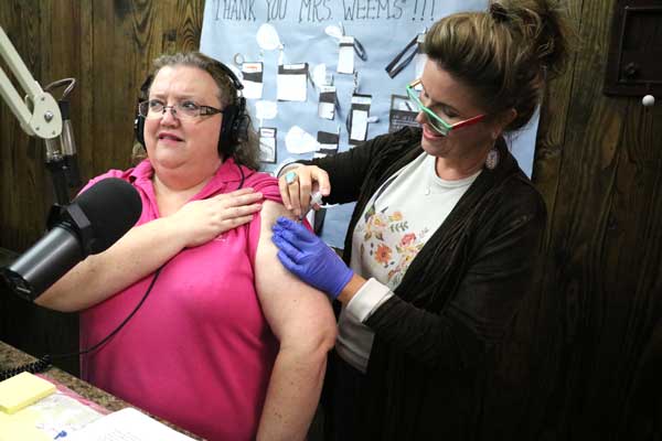 KBEY 103.9 FM Radio Picayune 'Wake Up Call' co-host Kay Baker gets a flu shot from Melinda Savage of Atkins Pharmacy.