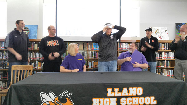 Llano High School senior Colton Center (middle) dons a University of Mary Hardin-Baylor visor after he signs his letter of intent to be a Crusader during a signing ceremony at Llano High School on Feb. 25. Also attending are Llano offensive coordinator Jarrett Vickers (left), line coach Bobby Williams, parents Jackie and Lance Center, Llano head coach Craig Slaughter and Llano High School Principal David Wuest. Staff photo by Jennifer Fierro