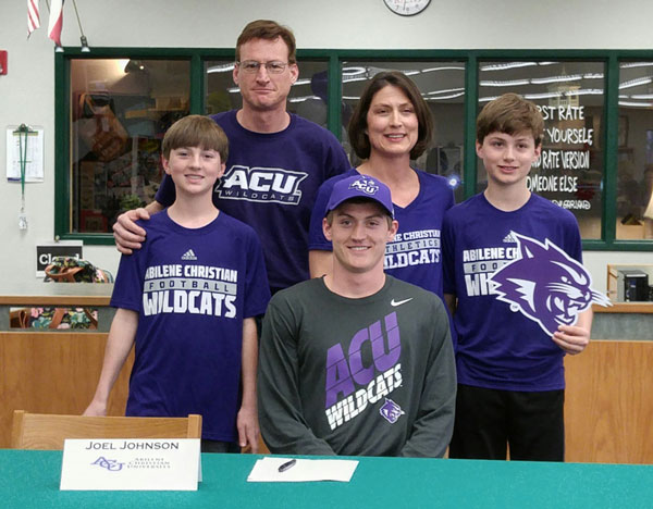 Burnet High School senior receiver Joel Johnson (seated) signs his letter of intent to play for Abilene Christian University on March 7 surrounded by his family: brother Ben (standing, left), parents Todd and Kim and brother Jacob. Staff photo by Jennifer Fierro