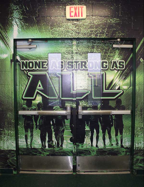 The door wrap on the double doors that lead to the gridiron at Bulldog Field features the Burnet football program’s saying: ‘None of us are as strong as all of us.’