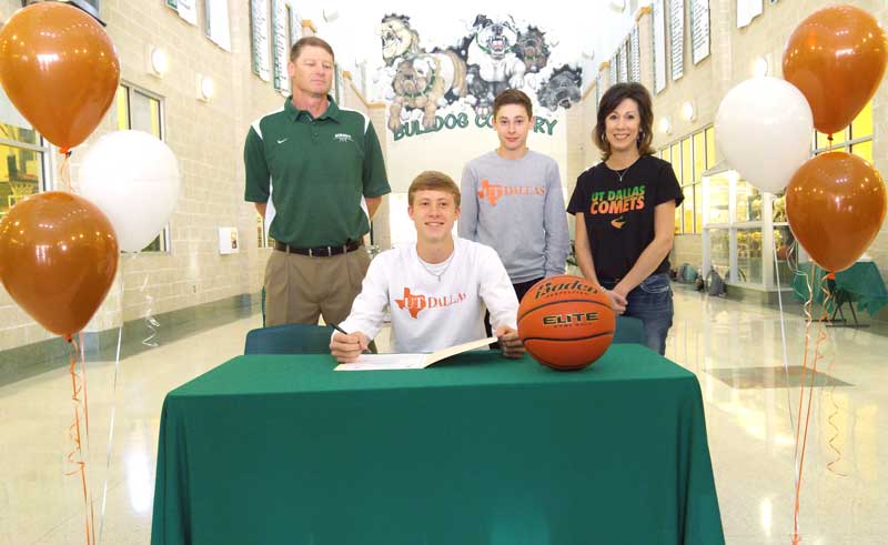 Burnet High School senior Drew Kiser signs his letter of intent to play basketball for the University of Texas-Dallas with his high school head coach and father, Roy Kiser (standing, left), younger brother, Luke, and mother, Gina, looking on. Staff photo by Jennifer Fierro