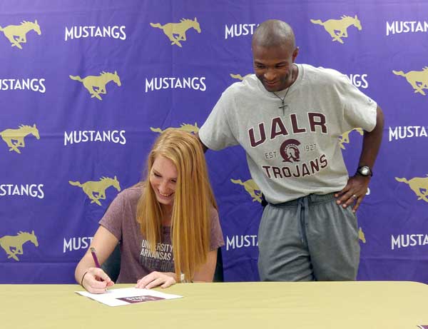 Marble Falls High School senior runner Kim Boni signs her letter of intent to compete for the University of Arkansas-Little Rock as Lady Mustangs head coach Anthony Torns looks on. Staff photo by Jennifer Fierro