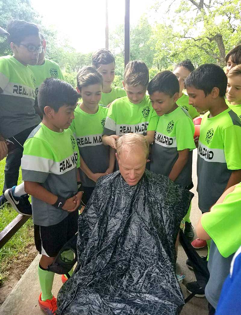 Real Madrid team members shave the head of assistant coach Chris Allen, who is also the Marble Falls Independent School District superintendent, after the team won the western district April 23 to advance to the state tournament. Courtesy photo