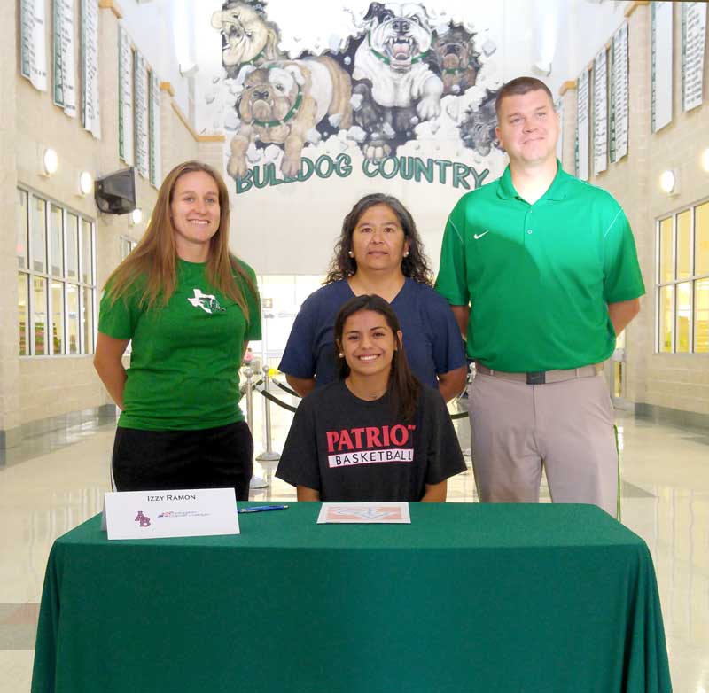 Burnet High School senior guard Izzy Ramon readies to sign her letter of intent to play for Arlington Baptist College as Lady Dawgs assistant coach Chelsea Sivells (standing, left), mother Tammy Ybarra, and Burnet head coach David Schubert look on. Staff photo by Jennifer Fierro
