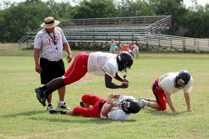 Faith Academy of Marble Falls head football coach Pete Rhoades watches as three players perform a ‘popcorn’ drill. The Flames open the season on the road Friday, Sept. 1, against the Center Point Pirates. Staff photo by Jennifer Fierro