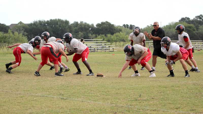 The Faith Academy of Marble Falls left side of the offensive line remains in place as center Issac Oliver snaps the ball to head coach Pete Rhoades. With Faith only suiting up 14 players on varsity, the team can’t practice 11 on 11, so Rhoades lines up at quarterback during practices. Staff photo by Jennifer Fierro