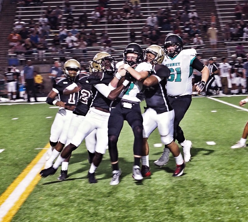 Burnet High School quarterback Chandler Galban hangs tight to the ball during a 19-yard run as several Austin Crockett Cougars try to bring him down and strip the ball. Staff photo by Daniel Clifton