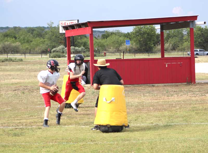 Faith Academy of Marble Falls assistant coach Jared Garza works with the quarterbacks during a recent practice. The Flames have canceled their Oct. 20 game against Waco Reicher due to not enough players. Staff photo by Jennifer Fierro