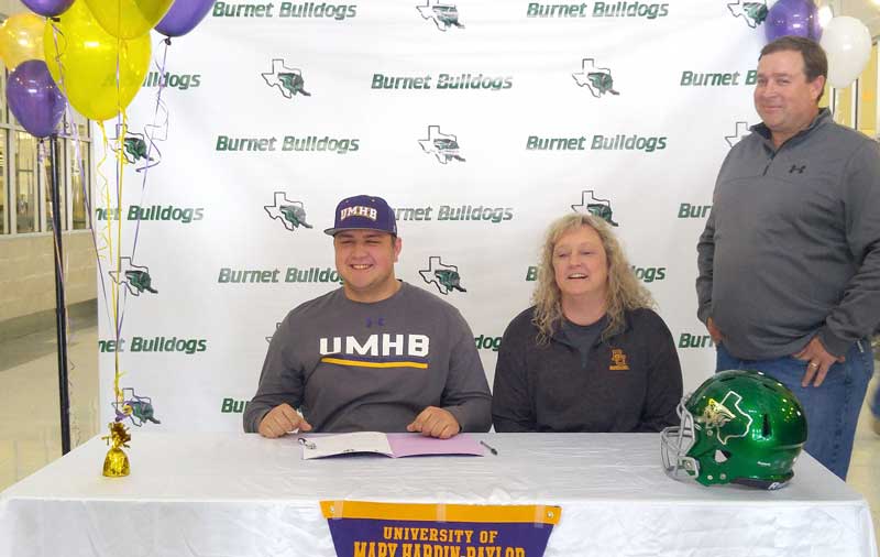 Burnet High School senior defensive lineman Seth Carpenter (left) signs his National Letter of Intent on Feb. 16 to play college football for the University of Mary Hardin-Baylor as parents Amanda and Brian Carpenter look on. Staff photo by Jennifer Fierro