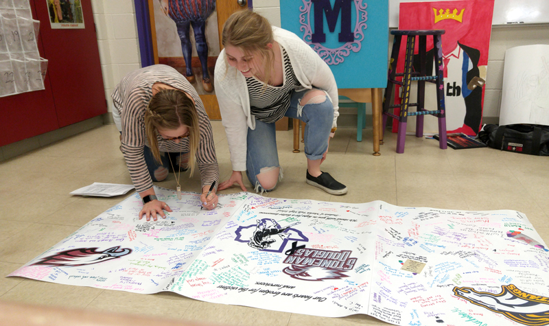 Marble Falls High School sophomore Kenadee Steward signs a banner that is being sent to the students at Marjory Stoneman Douglas High School in Parkland, Florida, while senior Anna Herrington looks for her message. Marjory Stoneman Douglas was the site of the latest school shooting on Feb. 14. Staff photo by Jennifer Fierro