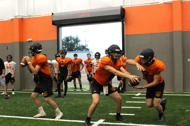Llano senior quarterback Cade Fly faked a handoff to senior running back Mason Brooks during the Yellow Jackets’ first day in shells Aug. 10. The team scrimmaged against Blanco on Aug. 17. Staff photo by Jennifer Fierro