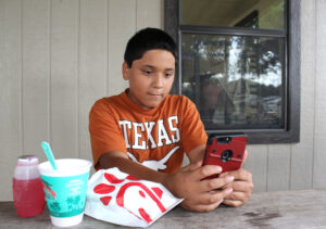Marble Falls Middle School sixth-grader Nathan Jowers watches a video on his smartphone thanks to the new Wi-Fi service at Westside Park. Jowers connected to the free service Aug. 9 while attending Westside Connection, a festive gathering hosted by the city of Marble Falls’s Community Engagement Initiative. Staff photo by Jennifer Fierro