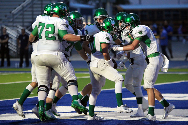Burnet sophomore running back Marcus Escamilla (10) is mobbed by his teammates, including senior offensive lineman Zac Hudgins (72) and sophomore receiver Luke Kiser (7), during the Bulldogs’ 46-0 victory of Manor New Tech on Sept. 21. Photo by Martelle Luedecke/Luedecke Photography