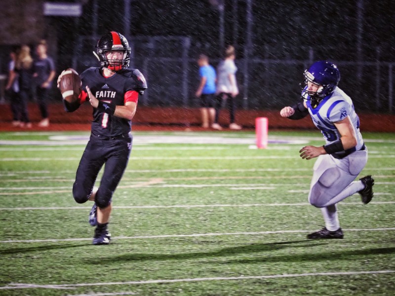 Faith Academy’s Travis Hughes looks for a receiver as an Austin Royals defender moves in on him. The Flames and Royals slogged through heavy rains during the first quarter with the showers returning off and on again throughout the contest. The Royals won 26-8. Staff photo by Daniel Clifton