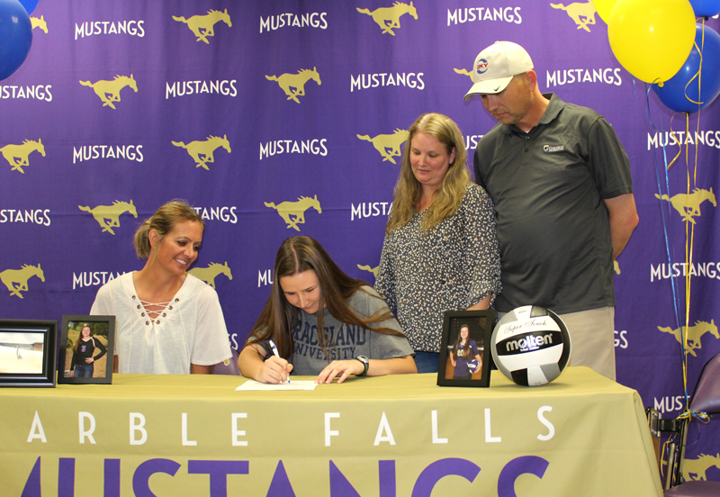 Marble Falls High School senior volleyball player Maddie Cline (seated, middle) signs her National Letter of Intent on Sept. 6 to play volleyball for Graceland University as Lady Mustangs head coach Tanya Powers (seated, left) and parents Jennifer and Matt Cline look on. Staff photo by Jennifer Fierro