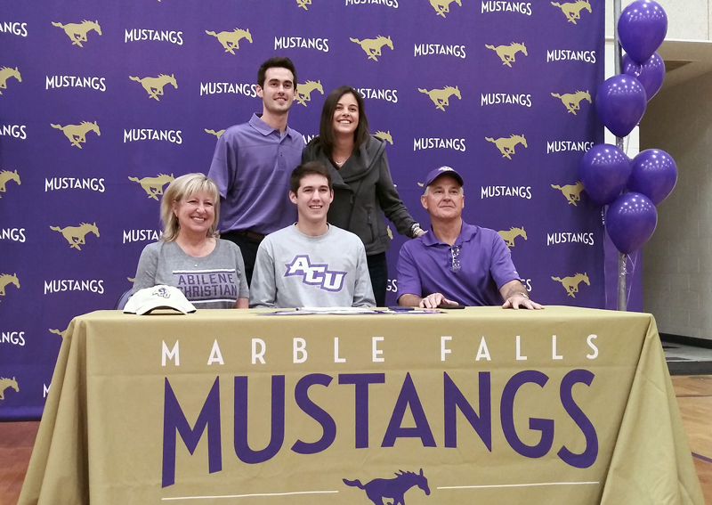Marble Falls High School senior quarterback Andrew Stripling (seated, middle) signed his National Letter of Intent to play for Abilene Christian University on Dec. 19 in Max Copeland Gym as parents Kay and Kyle Stripling (seated) and siblings Mike and Sarah looked on. Staff photo by Jennifer Fierro