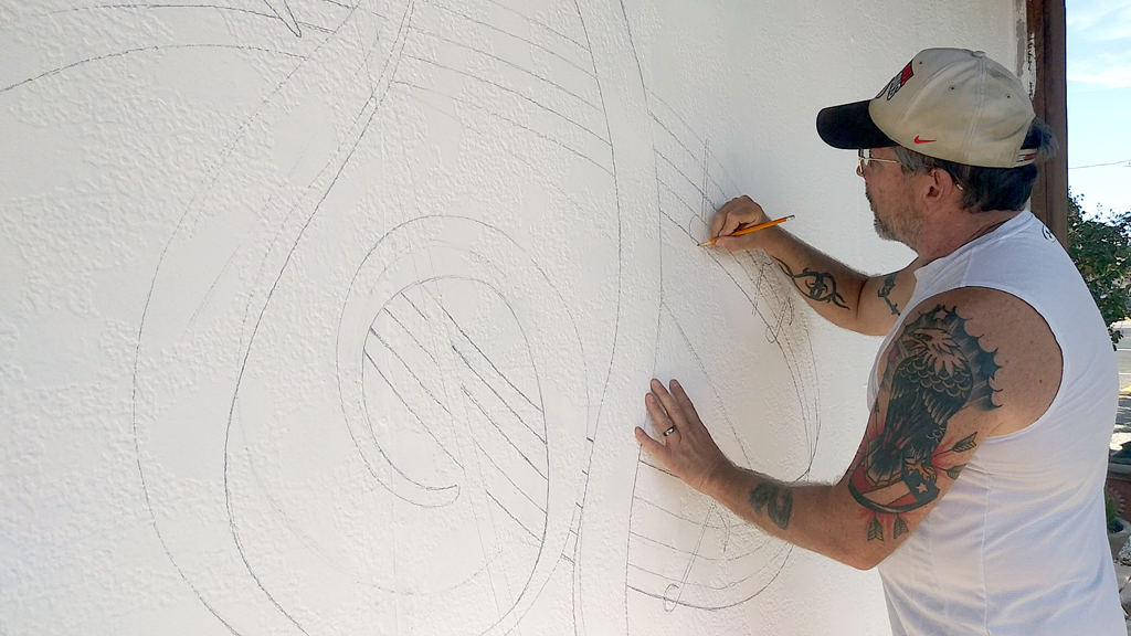 Artist and set designer Michael Fox pencils in a mural to be painted on the Hill Country Community Theatre building