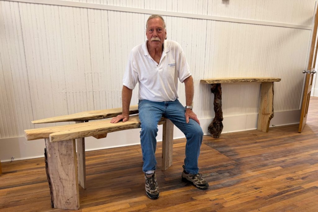 Rod Oberhaus sits on table he crafted